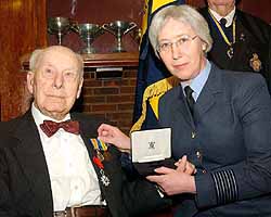 Group Captain Sue Bonell, Assistant Director MOD Medal Office, AFPAA, with 108 year old veteran, Mr Henry Allingham replacing his WW1 medals which were lost in the Blitz during WW2.